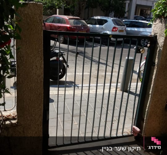 שער מתכת פתוח עם צללים על המדרכה
